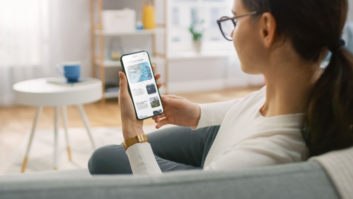 Frau mit Smartphone in der Hand sitzend auf Couch